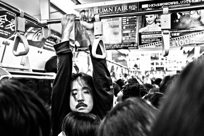 Japanese man hanging in a metro in Tokyo tired and in a crowd. Street Photography by Victor Borst