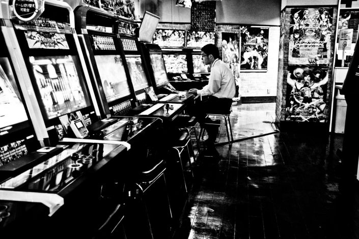 Japanese man playing an Arcade game in Akihabara, Tokyo. Street photography by Victor Borst