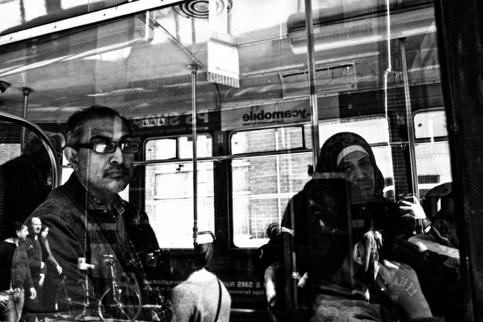 Window picture of people riding a bus in Antwerp with reflections. Street Photography by Victor Borst