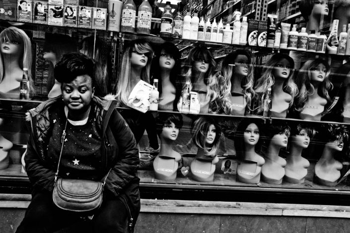 Portrait of an African woman in Brussels with a lot of faces with wigs. Street photography by victor borst