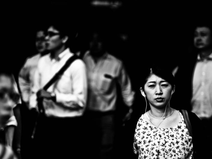 Salary woman with headphones listening to music at Shimbashi station. Street Photography by Victor Borst