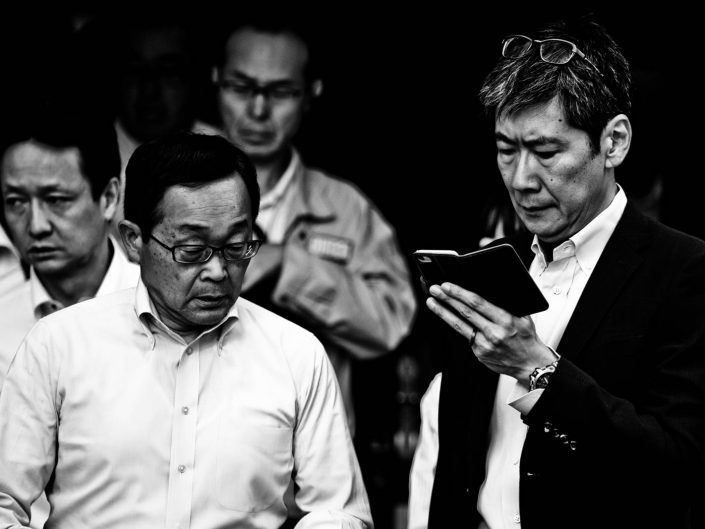 Man looking at his smartphone with glasses in his head in a Shimbashi crowd. Street Photography by Victor Borst
