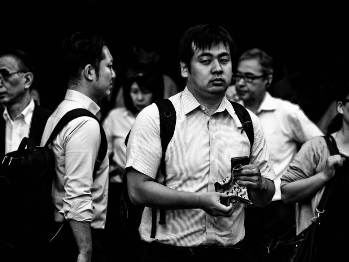 Some salarymen and women at Shimbashi station, one with a handkerchief. Street Photography by Victor Borst