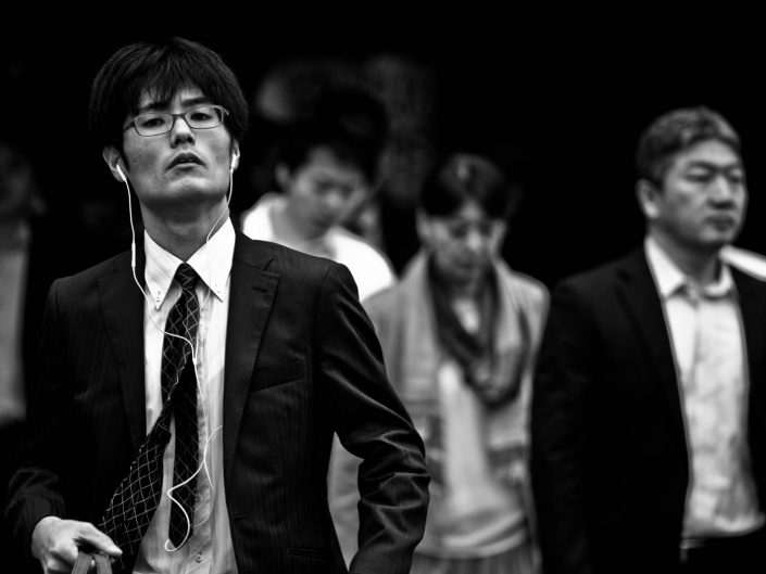 Portrait of a salaryman listening to some music with glasses. Street Photography by Victor Borst
