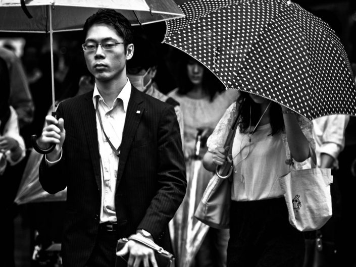 Portrait of a salaryman with umbrella and a woman with umbrella with dots. Street Photography by Victor Borst