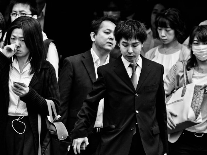 Group of salarymen and women at shimbashi station one with mask, one touching nose. Street Photography by Victor Borst