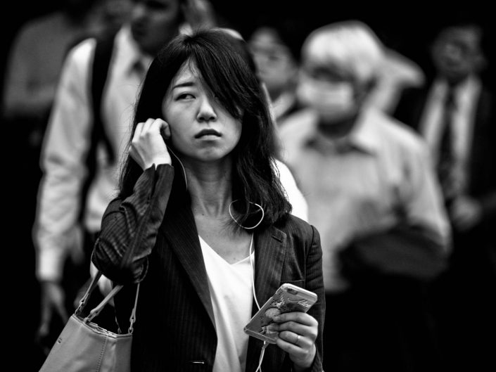 Portrait of an japanese woman at shimbashi station, listening to music on smartphone. Street Photography by Victor Borst